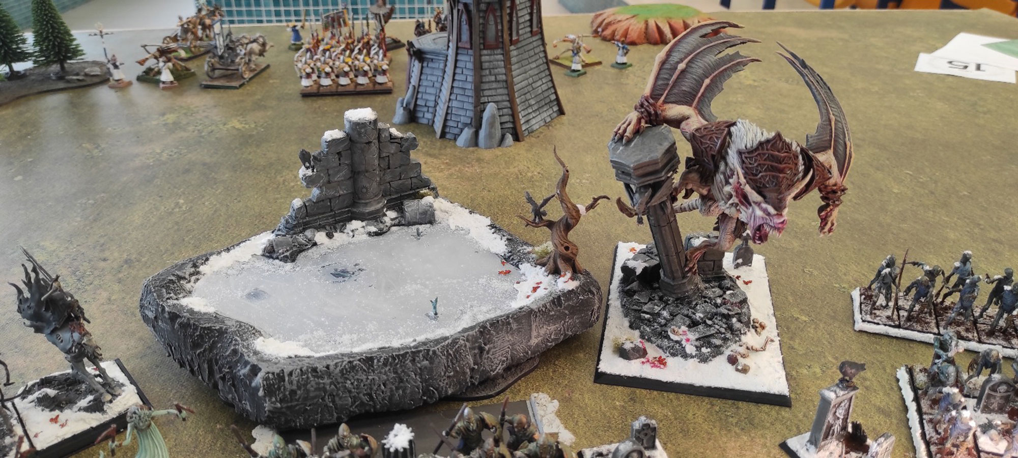 Mesa de Warhammer Fantasy con regimientos y una gran criatura alada durante una partida